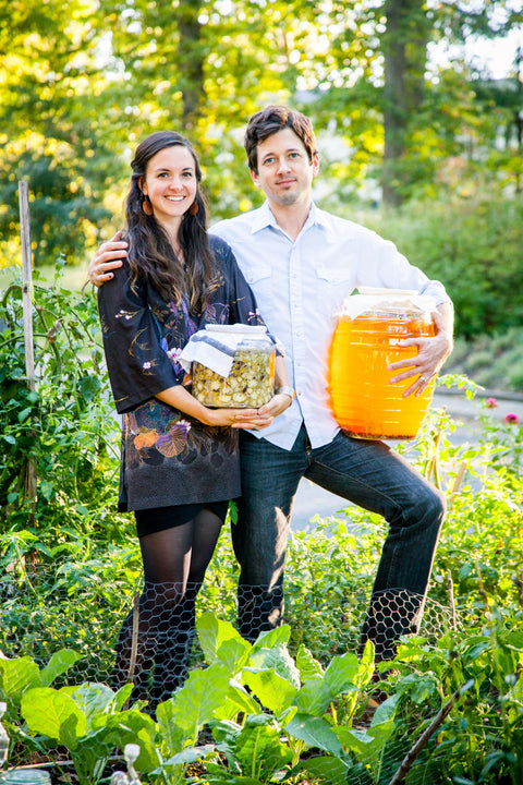 Meaghan and Shane Carpenter, owners of HEX Ferments, holding a large jar of fermented veggies and kombucha